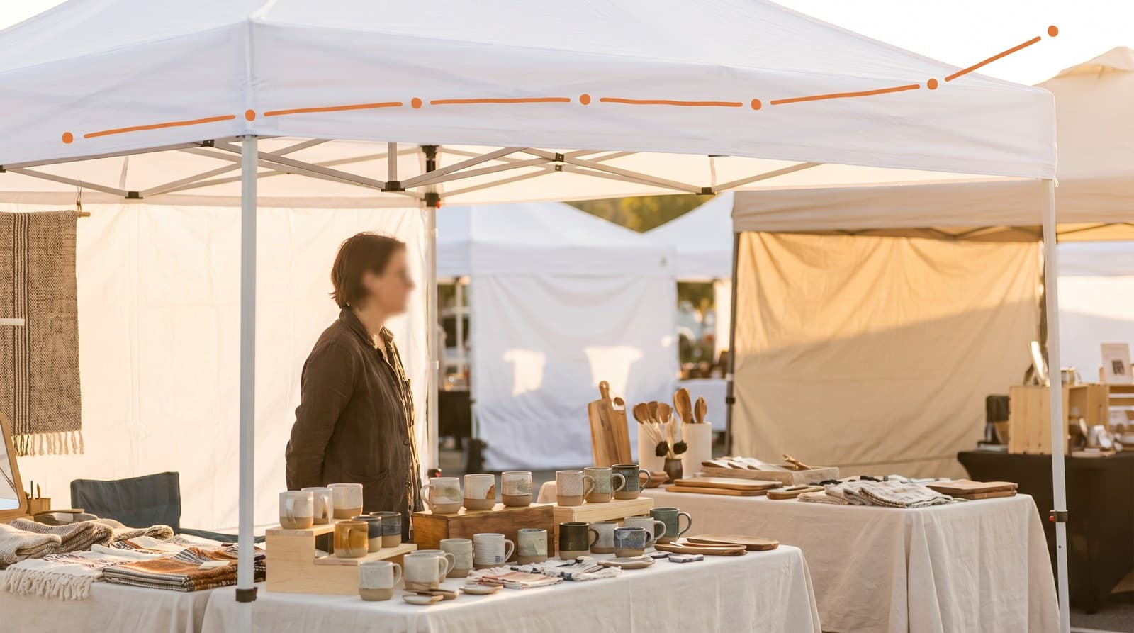 A vendor at a dialed-in booth with a hand-drawn rising line of ten small points arcing above, suggesting experience built over many events.